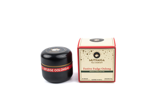 A packaged box of Festive Fudge, Premium Oolong tea in Kenya beside its sealed black container, both featuring branding and product name visible.