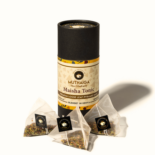 A package of Muthaiga Maisha Tonic tea, an organic herbal tea in Kenya,  with two silky pyramid bags visible in front of the package. The package has a black and yellow color scheme with text and branding.
