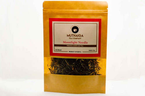 Packaged organic white tea in Kenya, labeled 'Moonlight Needle' by Muthaiga Tea Company, with visible dried leaves through the clear window