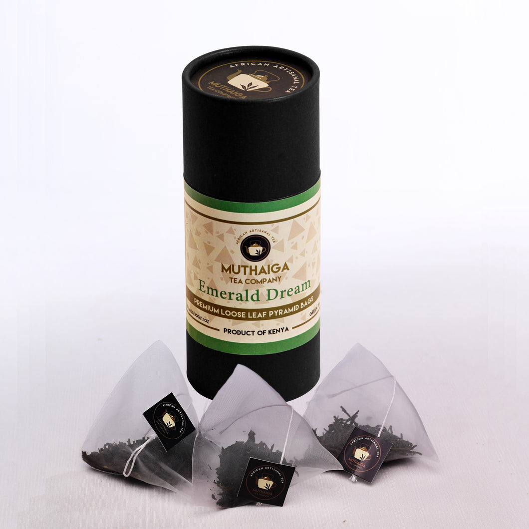 Product image of Muthaiga Emerald Dream, a premium organic green tea  in  biodegradable bags. The packaging is black with green and gold accents, and there are three clear pyramid bags with tea leaves visible in front.