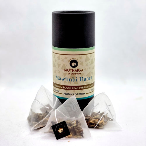 A package of Mawimbi Dance, loose leaf white tea bags in Kenya by Muthaiga Tea Company, featuring biodegradable pyramid tea bags with a label and a few loose leaf teas visible outside the package.